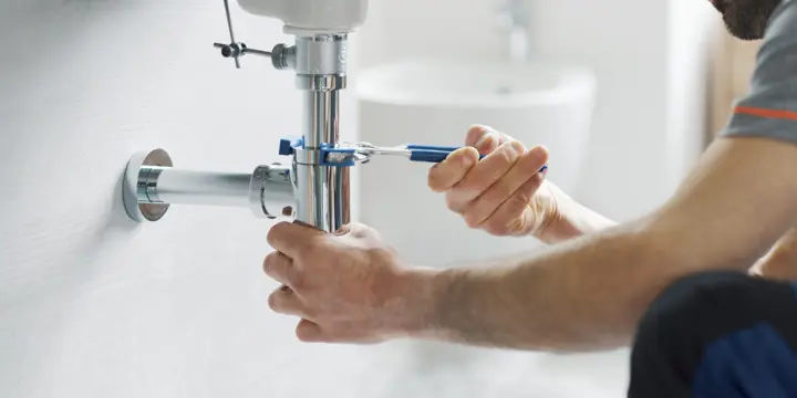 Plumber tightening a chrome sink drain connection