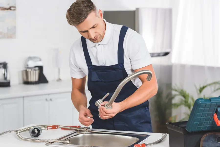 Plumber installing a chrome kitchen faucet